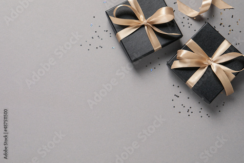 Beautiful gift boxes and confetti on grey background, flat lay. Space for text