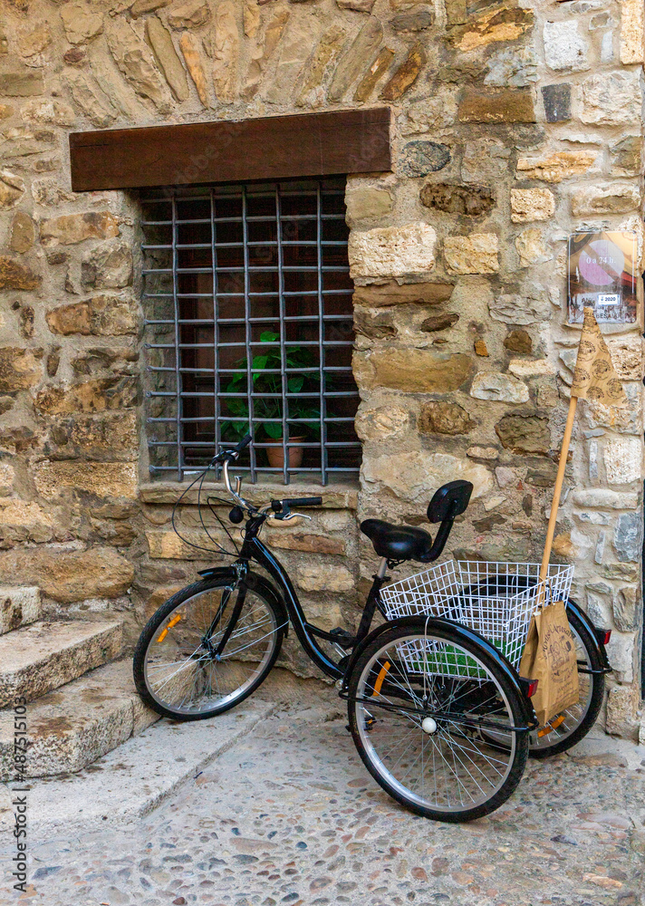 Classic black tricycle, with metal basket, parked in an old mediterranean street