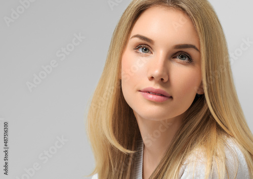Long smooth blonde hairstyle beauty woman close up portrait. Color background gray