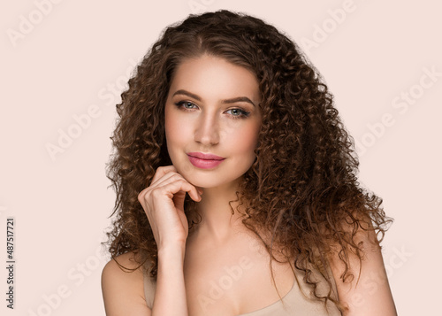 Curly long brunette hair young woman touching face beauty female portrait. Color backgound pink