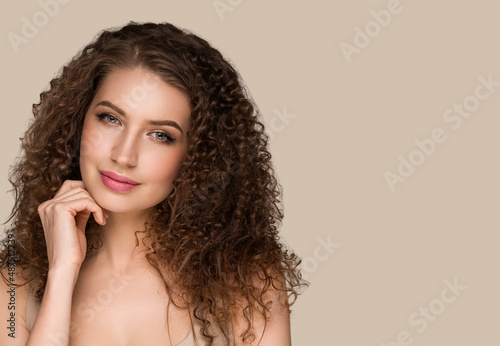 Curly long brunette hair young woman touching face beauty female portrait. Color backgound brown