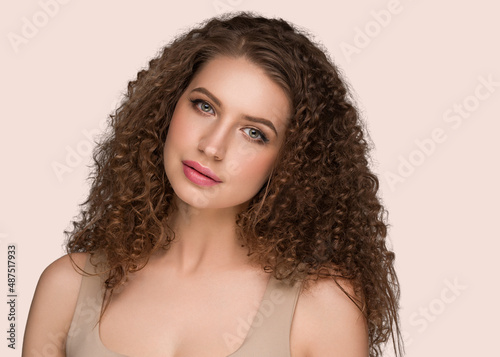 Curly long brunette hair woman beauty portrait, female glamour face. Color backgound pink