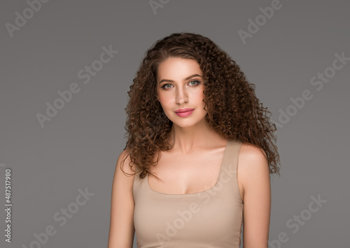 Curly long brunette hair woman beauty portrait, female glamour face. Color backgound gray