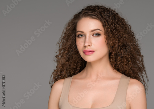 Curly long brunette hair woman beauty portrait, female glamour face. Color backgound gray