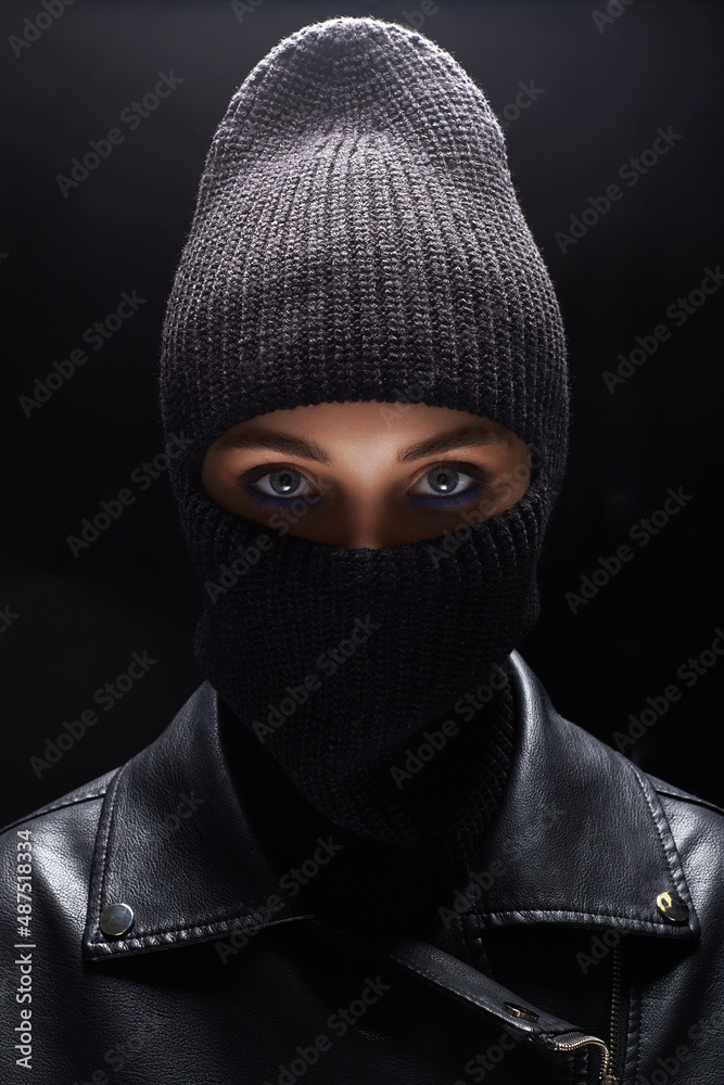 Fashionable girl in black balaclava and leather coat. Beautiful female eyes