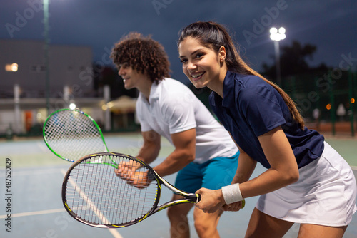 Young couple on tennis court. Handsome man and attractive woman are playing tennis. © NDABCREATIVITY
