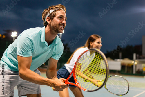 Tennis sport people concept. Mixed doubles player hitting tennis ball with partner standing near net © NDABCREATIVITY