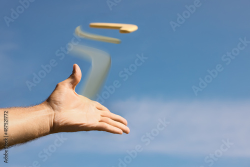 Man throwing boomerang against blue sky, closeup photo