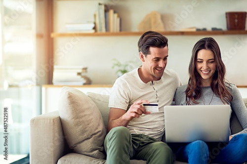 Lets treat ourselves. Weve earned it. Shot of a happy young couple making a credit card payment on a laptop together at home.
