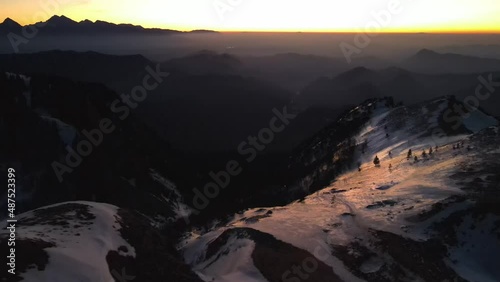 Drone video up in the mountains at a beautiful very early sunrise with mountains captured in amazing morning colors and landscape covered in snow captured in Slovenia on a mountains Ratitovec photo