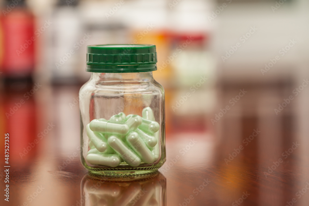 glass jar with green capsule glass jar with green capsule