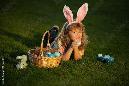 Bunny kids with rabbit bunny ears. Child with easter eggs in basket outdoor. Boy laying on grass in park. Easter egg hunt. Fynny kids portrait.