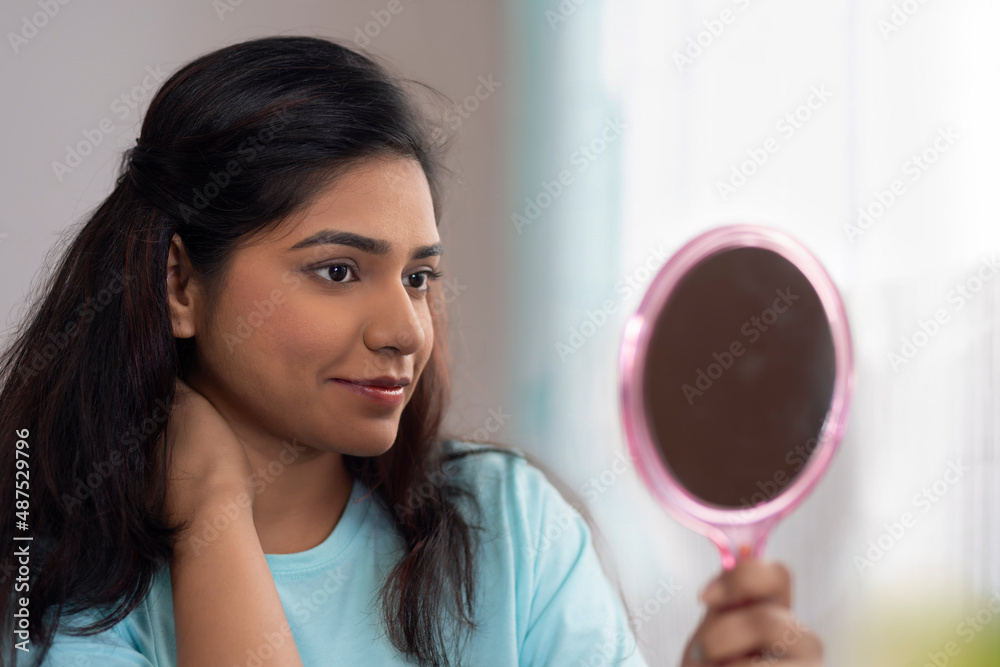 Portrait of young woman looking at herself in a little mirror Portrait of young woman looking at herself in a little mirror