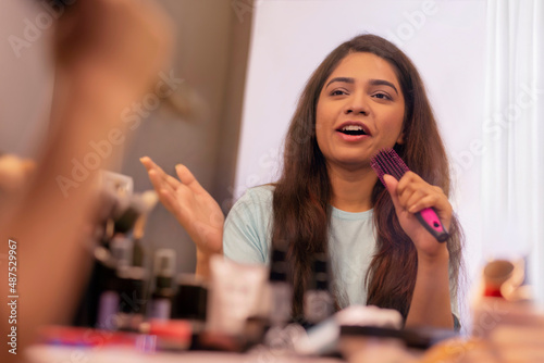 Young Woman Holding Hairbrush While Singing at makeup room
