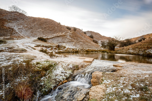Winter scenes of the Wash pool on Cleeve Hill, Gloucestershire. Snow covered hills and frost covered grass. photo