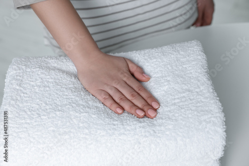 Woman touching soft white towel indoors  closeup