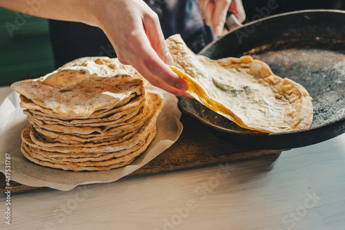 baker's hands are removing pita bread from a cast-iron frying pan.