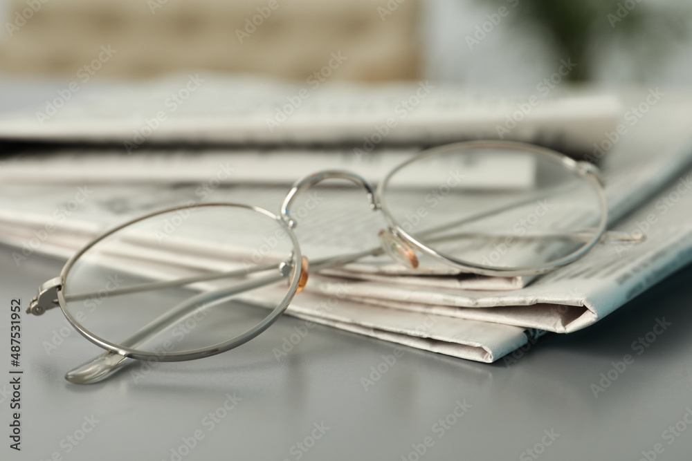 Newspapers and glasses on grey table, closeup Newspapers and glasses on grey table, closeup