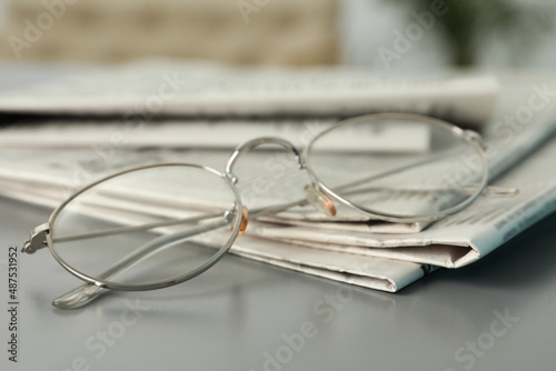 Newspapers and glasses on grey table, closeup