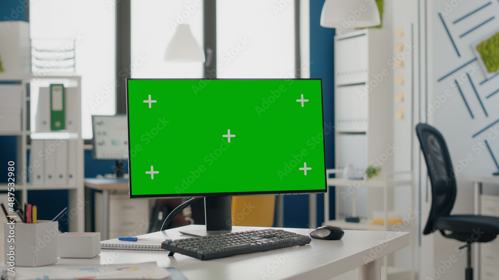 Close up of green screen on computer monitor at empty desk. Device with isolated mock up template and background with chroma key app, blank mock-up display and copy space technology.