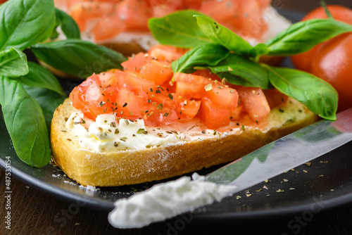 Tasty savory tomato Italian appetizers, or bruschetta, on slices of toasted baguette garnished with basil, close up