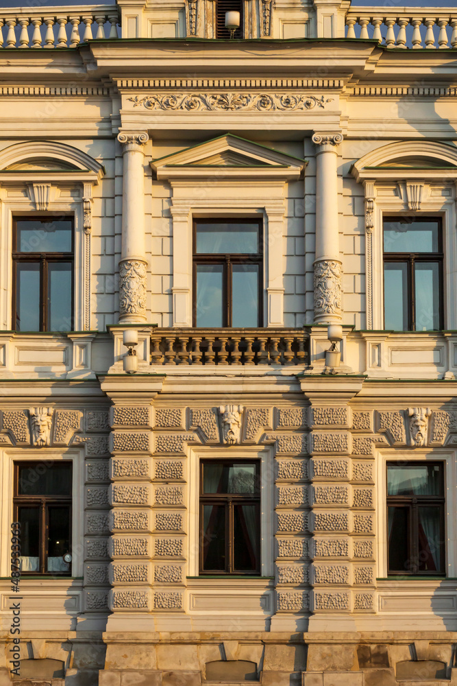 Facade of the old building with carved columns, balustrade, attic and other architectural decorations. Front view.