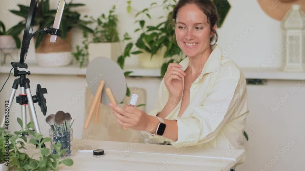 A young woman beauty blogger broadcasts live streaming to review makeup and cosmetic products on social media.A woman applies lip gloss with her finger.Slow motion. A young woman beauty blogger broadcasts live streaming to review makeup and cosmetic products on social media.A woman applies lip gloss with her finger.Slow motion.