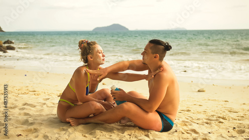 Cute loving couple each other having sun block. Woman to put sunscreen man. Young girl and guy face to face using sun cream. Concept rest tropical resort, traveling tourism happy summer holidays