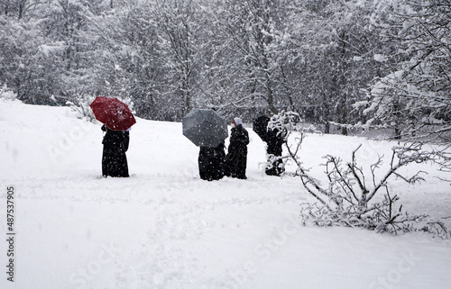 Gruppo di persone con ombrello cammina sotto la nevicata invernale