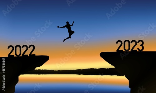A man is jumping over to cliff and jump across between 2022 and 2023 word.
