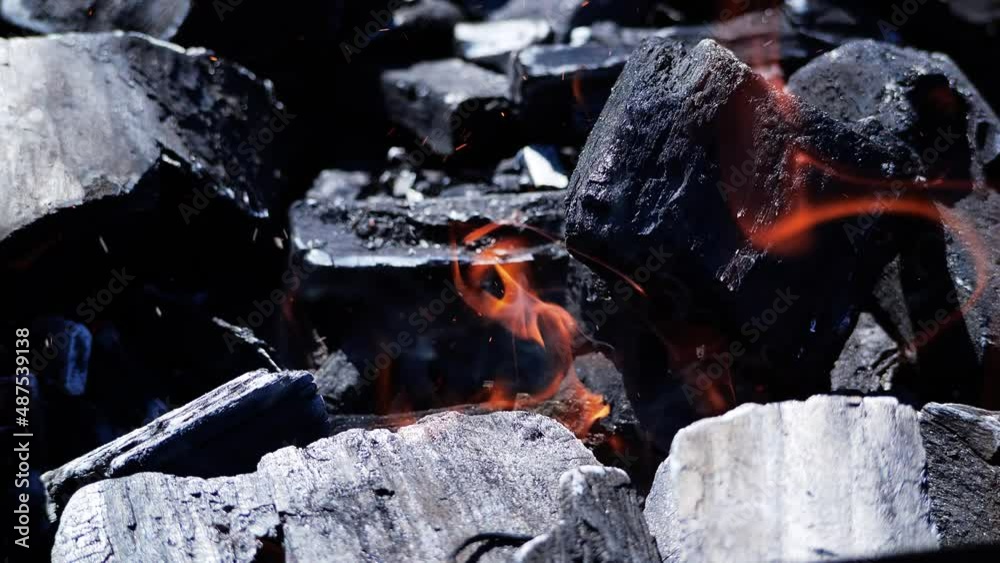 Slow motion orange fire flame burning on charcoal. Coal burn in the fire in slow motion. Close up of burning coals in the barbecue grill. 4K footage Slow motion orange fire flame burning on charcoal. Coal burn in the fire in slow motion. Close up of burning coals in the barbecue grill. 4K footage