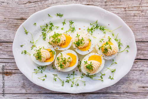 Boiled egg halves decorated with watercress. Easter egg snacks.