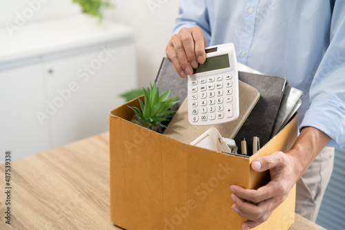 Business man sending resignation letter and packing Stuff Resign Depress or carrying business cardboard box by desk in office. Change of job or fired from company. © Charlie's