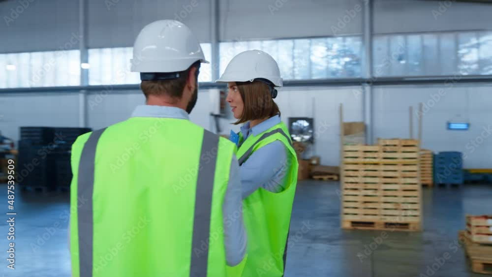 Warehouse specialists checking factory production holding tablet papers talking Warehouse specialists checking factory production holding tablet papers talking