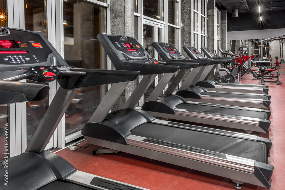 Lined contemporary speedwalks by the window in spacious, well lit, empty gym interior. Special modern equipment for physical training. Sport, fitness