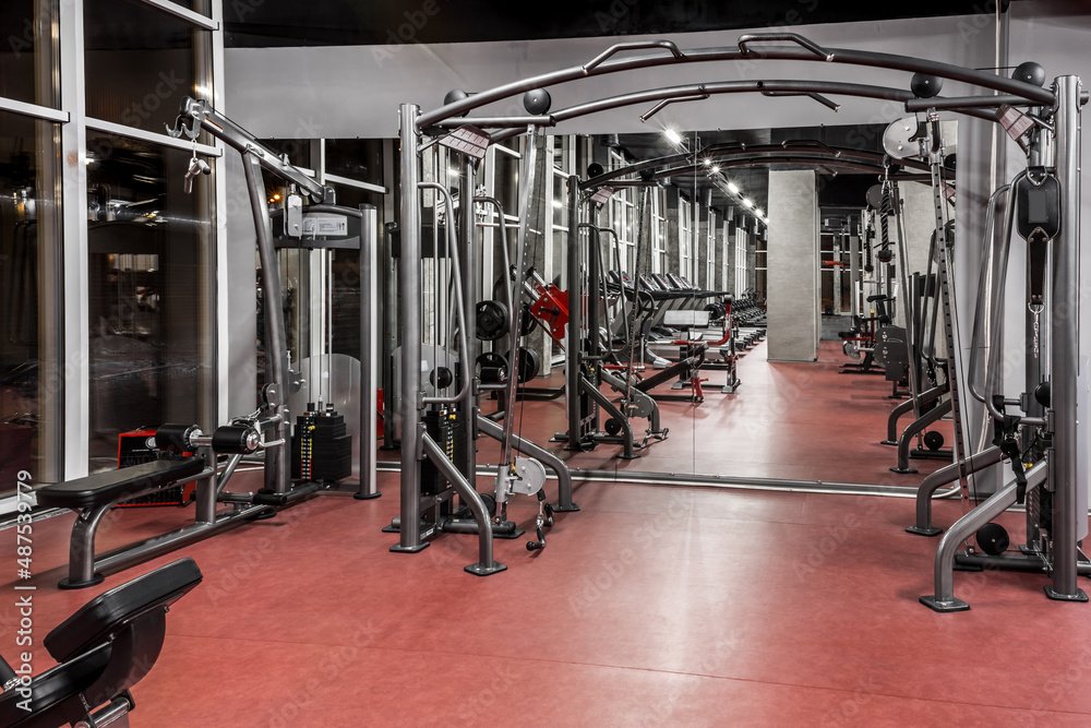 Exercise machines for physical training in spacious, well lit, empty gym interior with huge mirror. Special modern equipment. Sport, fitness Exercise machines for physical training in spacious, well lit, empty gym interior with huge mirror. Special modern equipment. Sport, fitness