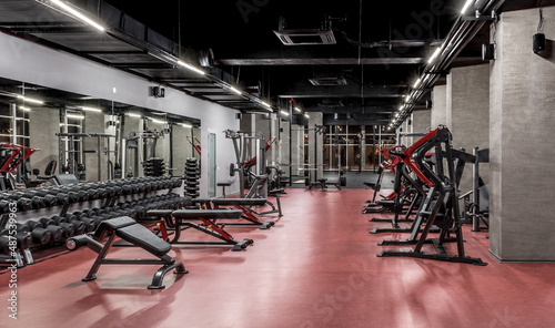Exercise machines and racks with sets of black weights by the mirror in empty gym interior. Special equipment for physical training. Sport, fitness