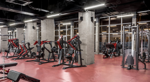 Strength equipment for body training in spacious, well lit, empty gym interior with huge windows. Modern exercise machines. Sport, fitness