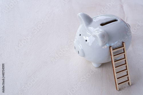 A wooden staircase leads to the goal of success in saving money and a piggy bank is placed next to each other on the office table. financial planning for efficiency concept.