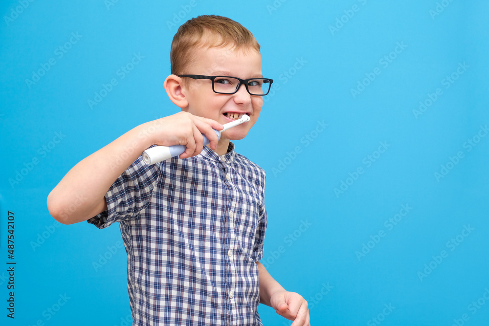 the boy is brushing his teeth. A small child with a toothbrush on a blue background