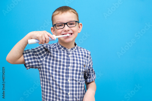 the boy is brushing his teeth. A small child with a toothbrush on a blue background
