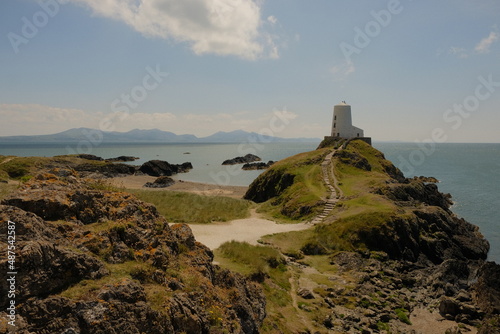 Old lighthouse in Anglesey with sand and greenery and rocks