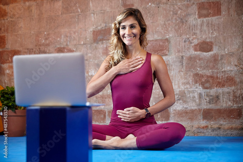 Young woman doing online yoga classes with her laptop