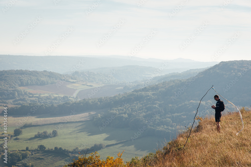Un homme à la montagne regardant son téléphone. Un homme regardant un panorama. Un homme sur un panorama avec une manche à air.