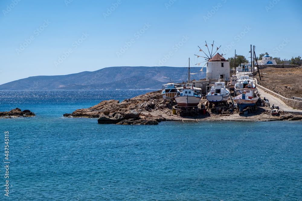 Greece. Koufonisi island, Cyclades. Windmill, shipyard for wooden fishing boat, sea, blue sky.