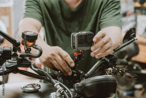 motorcycle mechanic installing action sports camera into motorcycle handle bar at garage .maintenance,repair concept in garage .selective focus