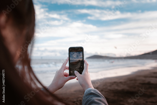 Chica sacando fotografías con el móvil en una playa de Islas Canarias photo