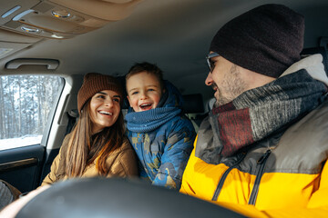 Mother, father and child traveling by car on a vacation to the mountains in winter