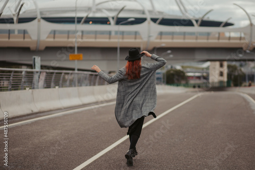 young woman with red hair jumping and running on the road