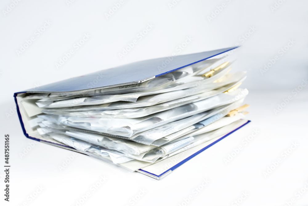 Large ring binder with clear punched pockets full of receipts, office management, accounting and tax calculation, light gray background, copy space, selected focus Large ring binder with clear punched pockets full of receipts, office management, accounting and tax calculation, light gray background, copy space, selected focus